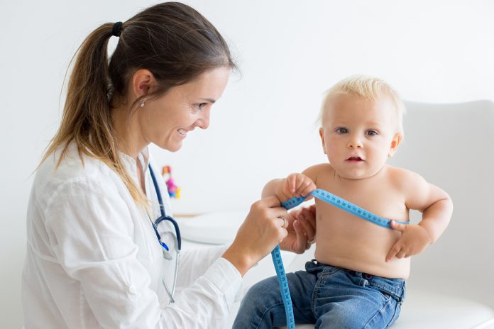Pediatrician Examining Baby Boy. Doctor Using Stethoscope To Lis